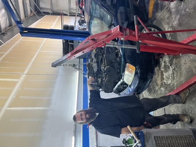 Mechanic with engine lift working on a vehicle